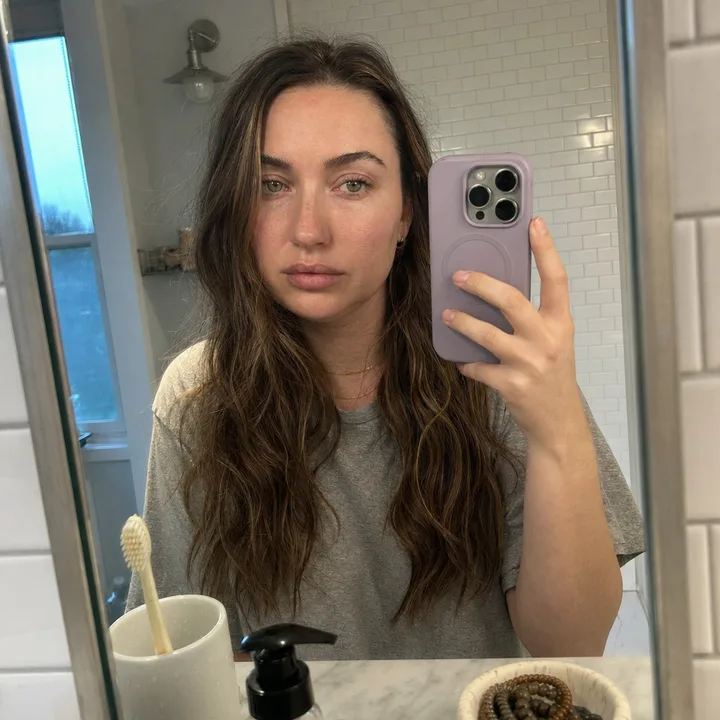 Day 1: Maya in her bathroom mirror, morning, puffy, no makeup